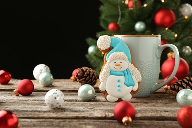 Photo of Delicious cookie in shape of snowman, cup with cocoa and Christmas decor on wooden table