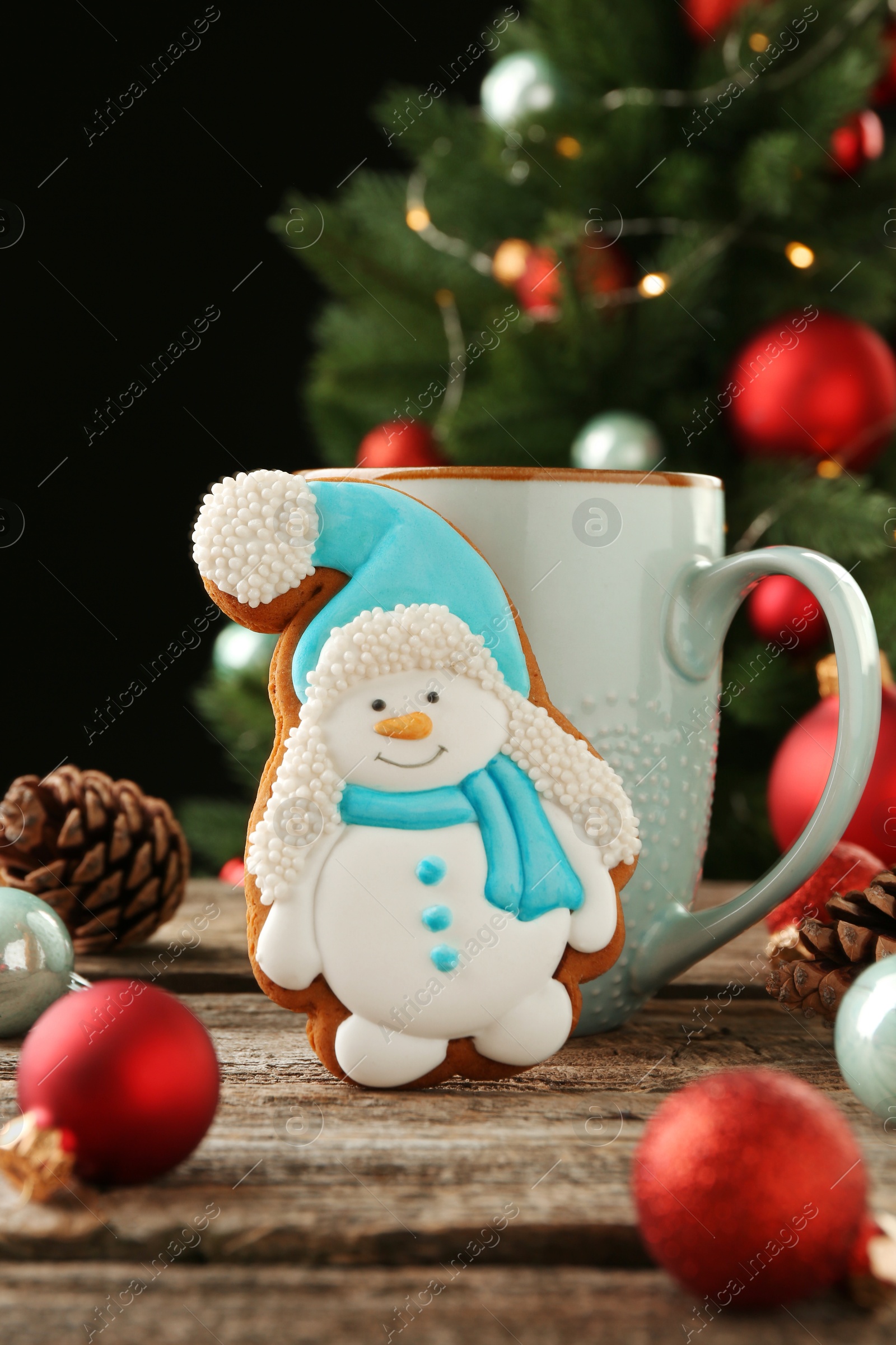 Photo of Delicious cookie in shape of snowman, cup with cocoa and Christmas decor on wooden table