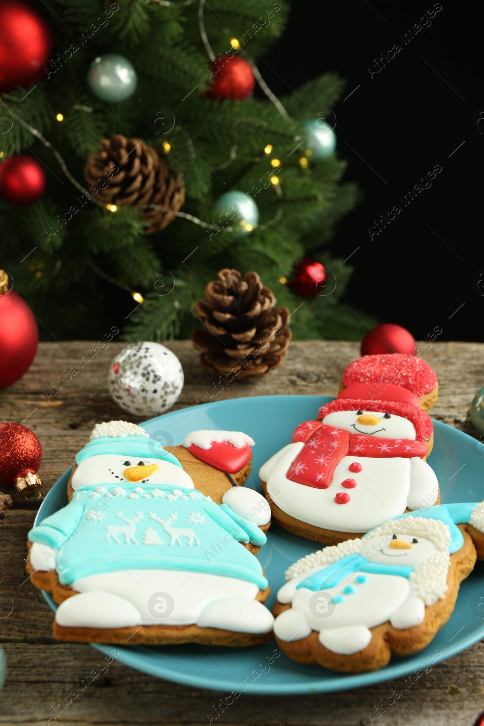 Photo of Delicious cookies in shape of snowmen and Christmas decor on wooden table