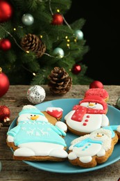 Photo of Delicious cookies in shape of snowmen and Christmas decor on wooden table