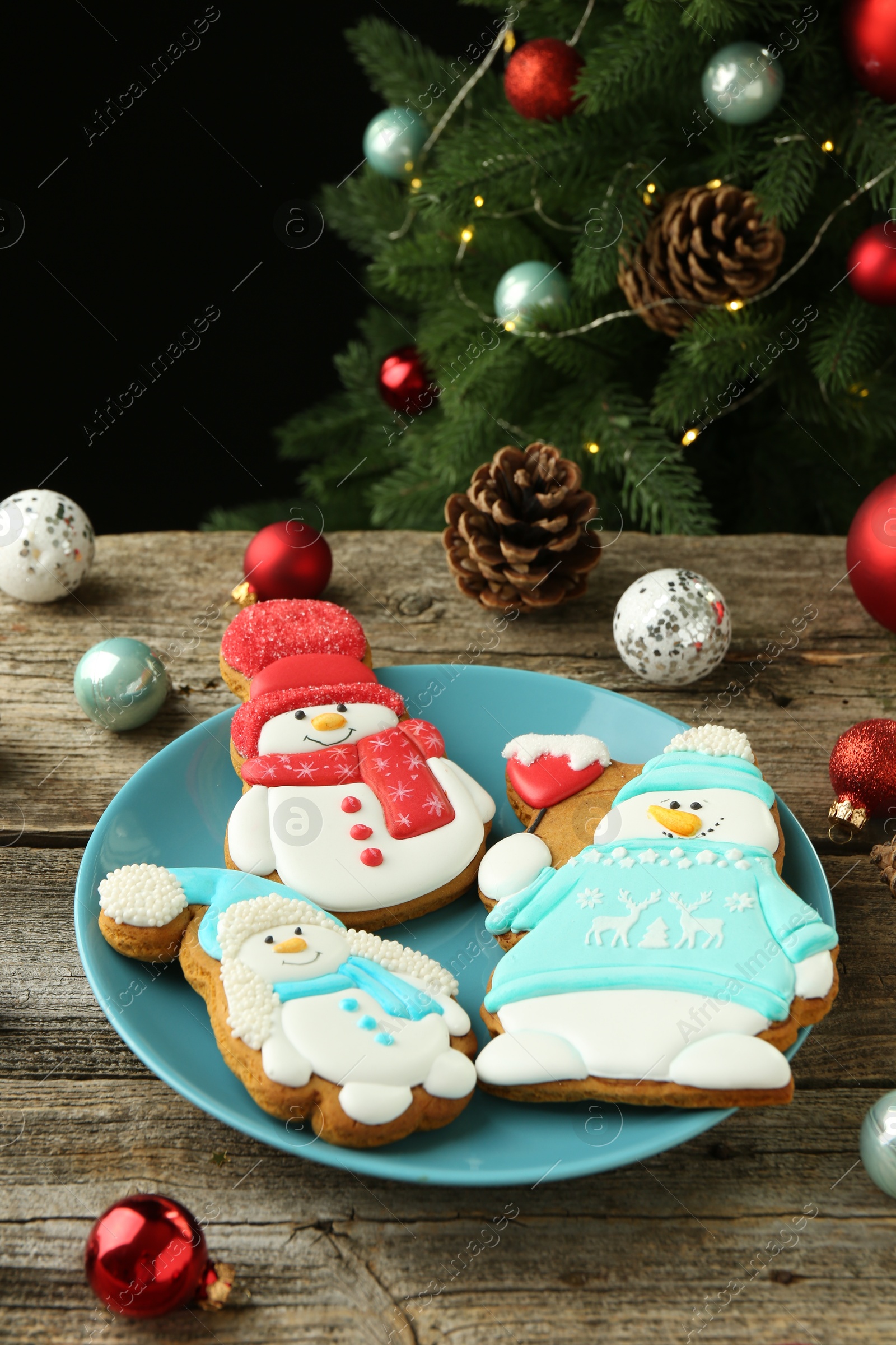 Photo of Delicious cookies in shape of snowmen and Christmas decor on wooden table