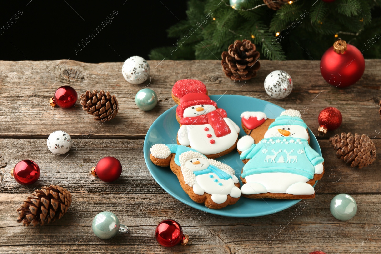 Photo of Delicious cookies in shape of snowmen and Christmas decor on wooden table