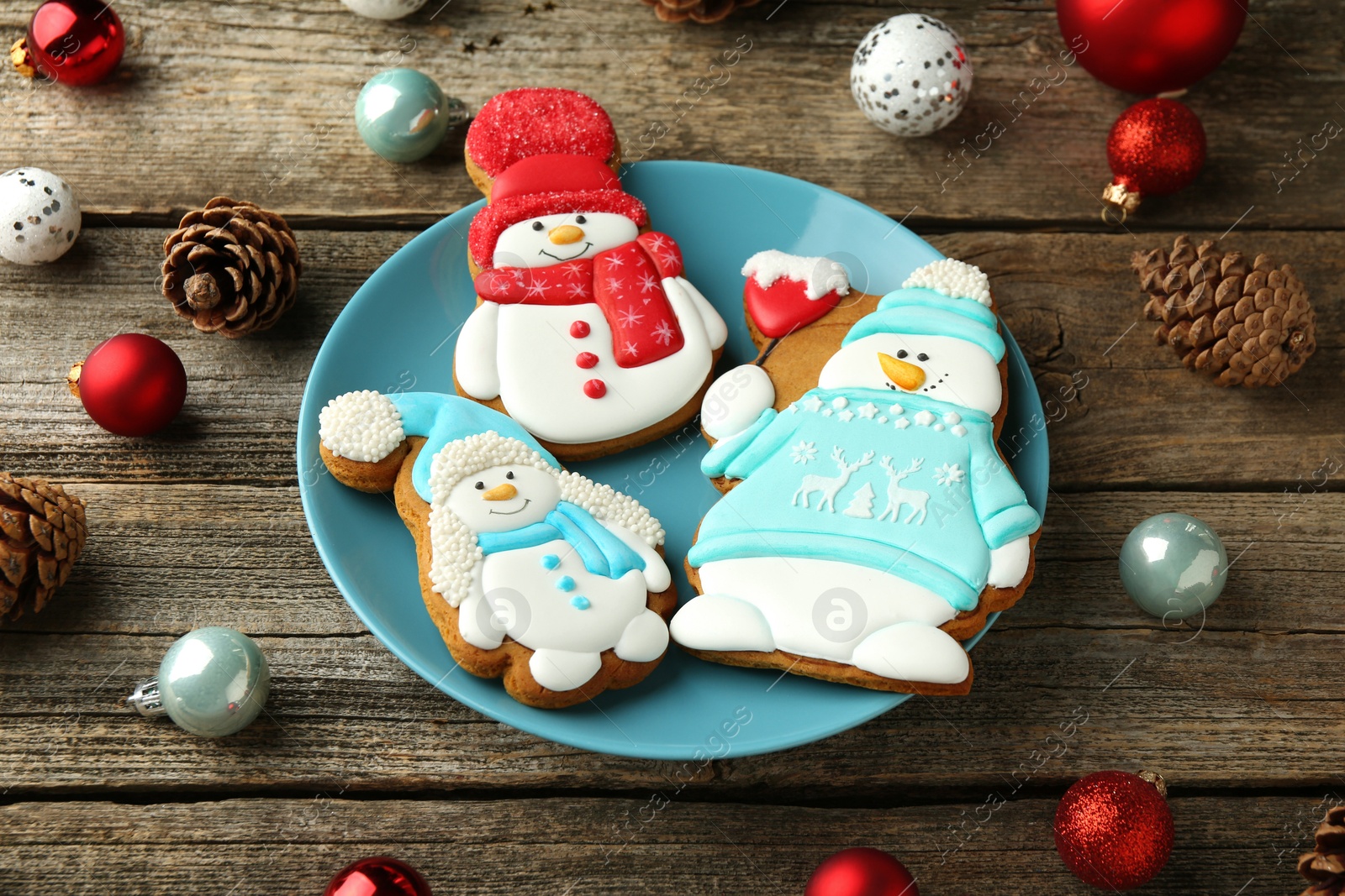 Photo of Delicious cookies in shape of snowmen and Christmas decor on wooden table