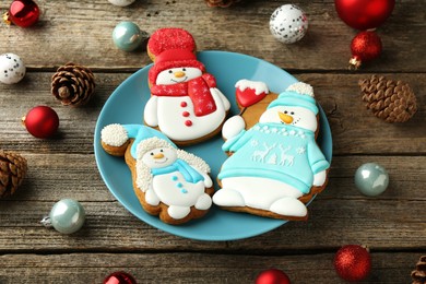 Photo of Delicious cookies in shape of snowmen and Christmas decor on wooden table