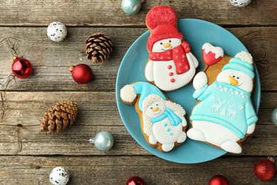 Photo of Delicious cookies in shape of snowmen and Christmas decor on wooden table, flat lay