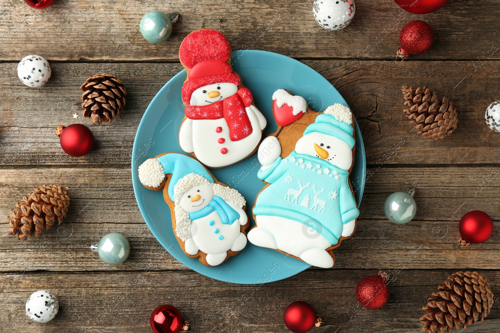 Photo of Delicious cookies in shape of snowmen and Christmas decor on wooden table, flat lay