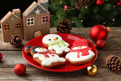 Photo of Delicious cookies in shape of snowmen and Christmas decor on wooden table