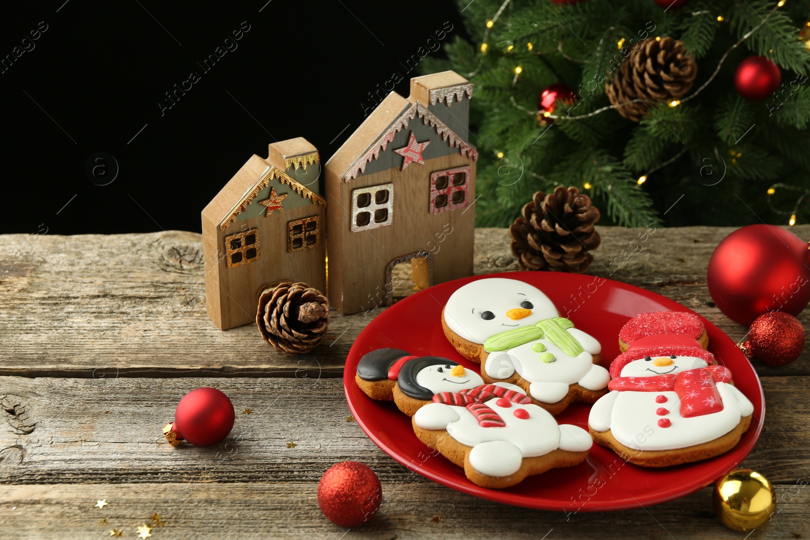 Photo of Delicious cookies in shape of snowmen and Christmas decor on wooden table