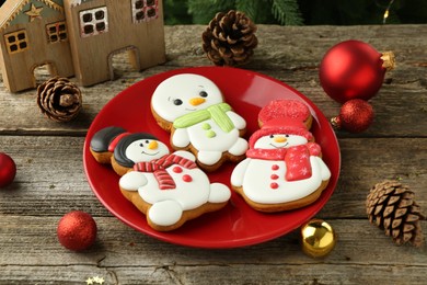 Photo of Delicious cookies in shape of snowmen and Christmas decor on wooden table