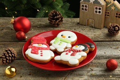 Photo of Delicious cookies in shape of snowmen and Christmas decor on wooden table