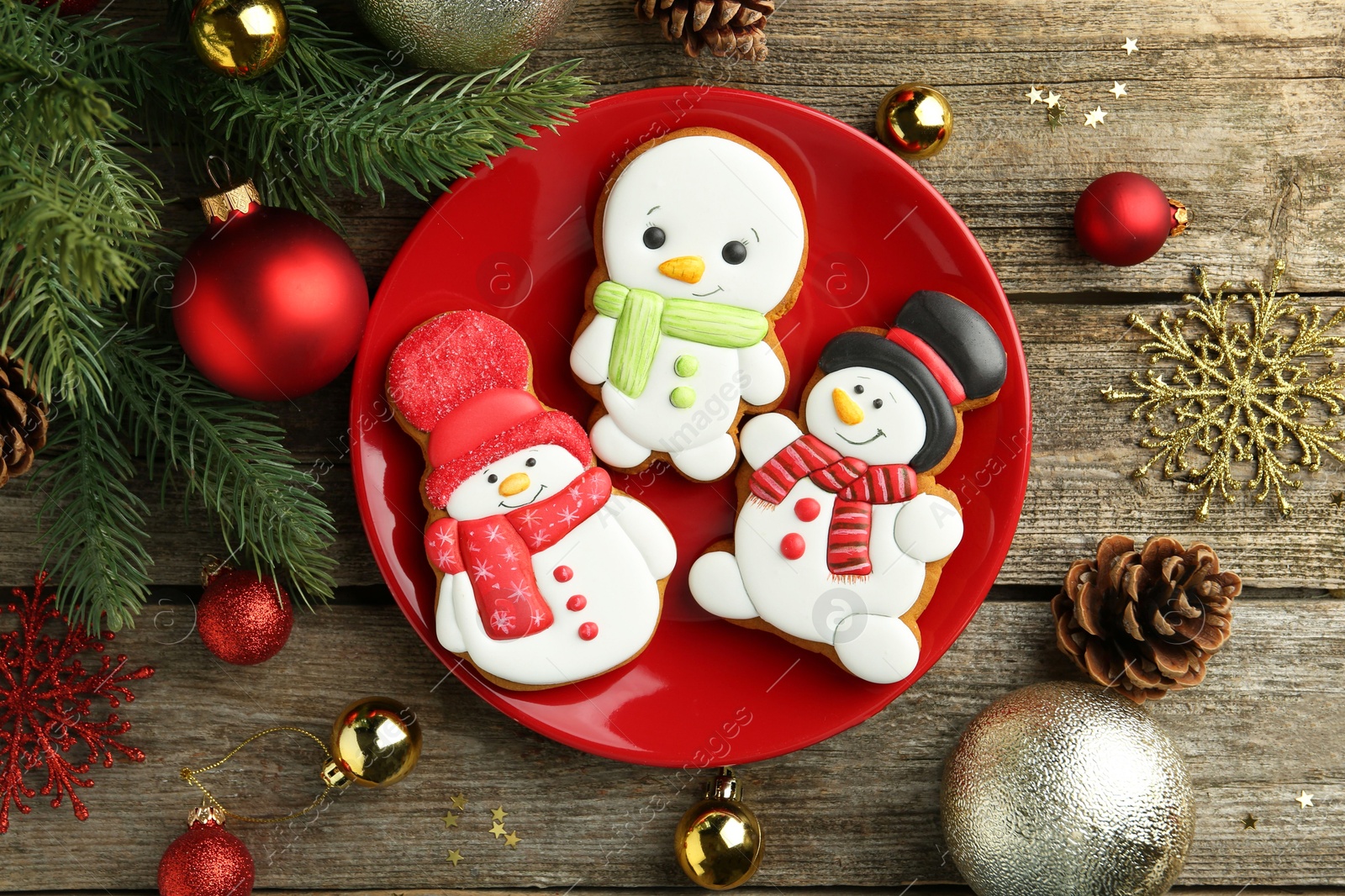 Photo of Delicious cookies in shape of snowmen and Christmas decor on wooden table, flat lay