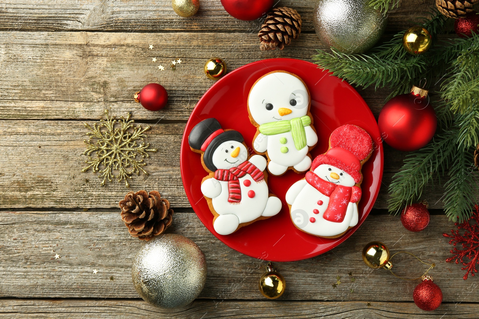 Photo of Delicious cookies in shape of snowmen and Christmas decor on wooden table, flat lay