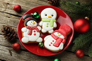 Photo of Delicious cookies in shape of snowmen and Christmas decor on wooden table, above view