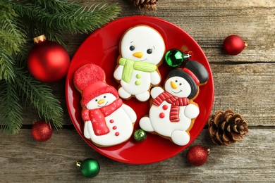 Photo of Delicious cookies in shape of snowmen and Christmas decor on wooden table, flat lay