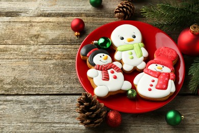 Photo of Delicious cookies in shape of snowmen and Christmas decor on wooden table, above view. Space for text