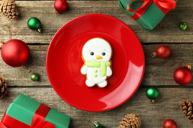 Photo of Delicious cookie in shape of snowman and Christmas decor on wooden table, flat lay