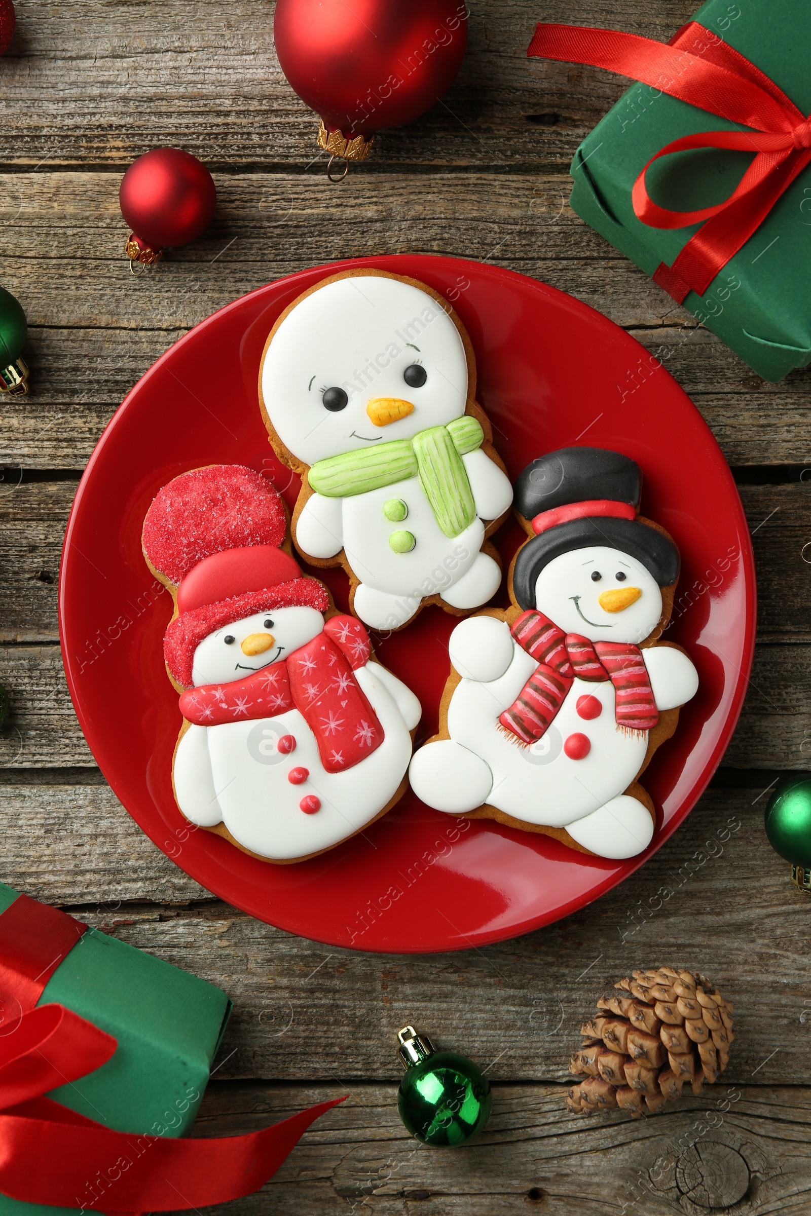 Photo of Delicious cookies in shape of snowmen and Christmas decor on wooden table, flat lay