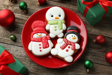 Photo of Delicious cookies in shape of snowmen and Christmas decor on wooden table, above view