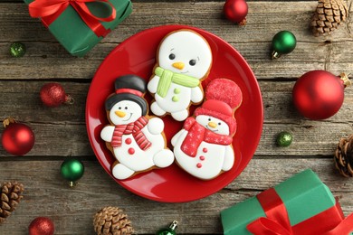 Photo of Delicious cookies in shape of snowmen and Christmas decor on wooden table, flat lay