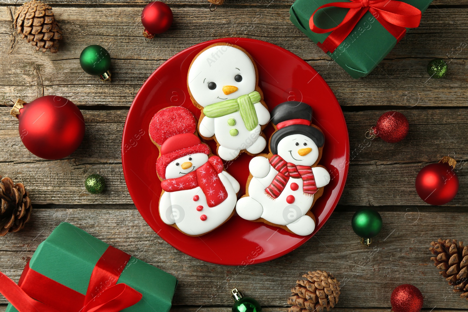 Photo of Delicious cookies in shape of snowmen and Christmas decor on wooden table, flat lay