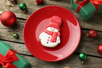 Photo of Delicious cookie in shape of snowman and Christmas decor on wooden table, flat lay