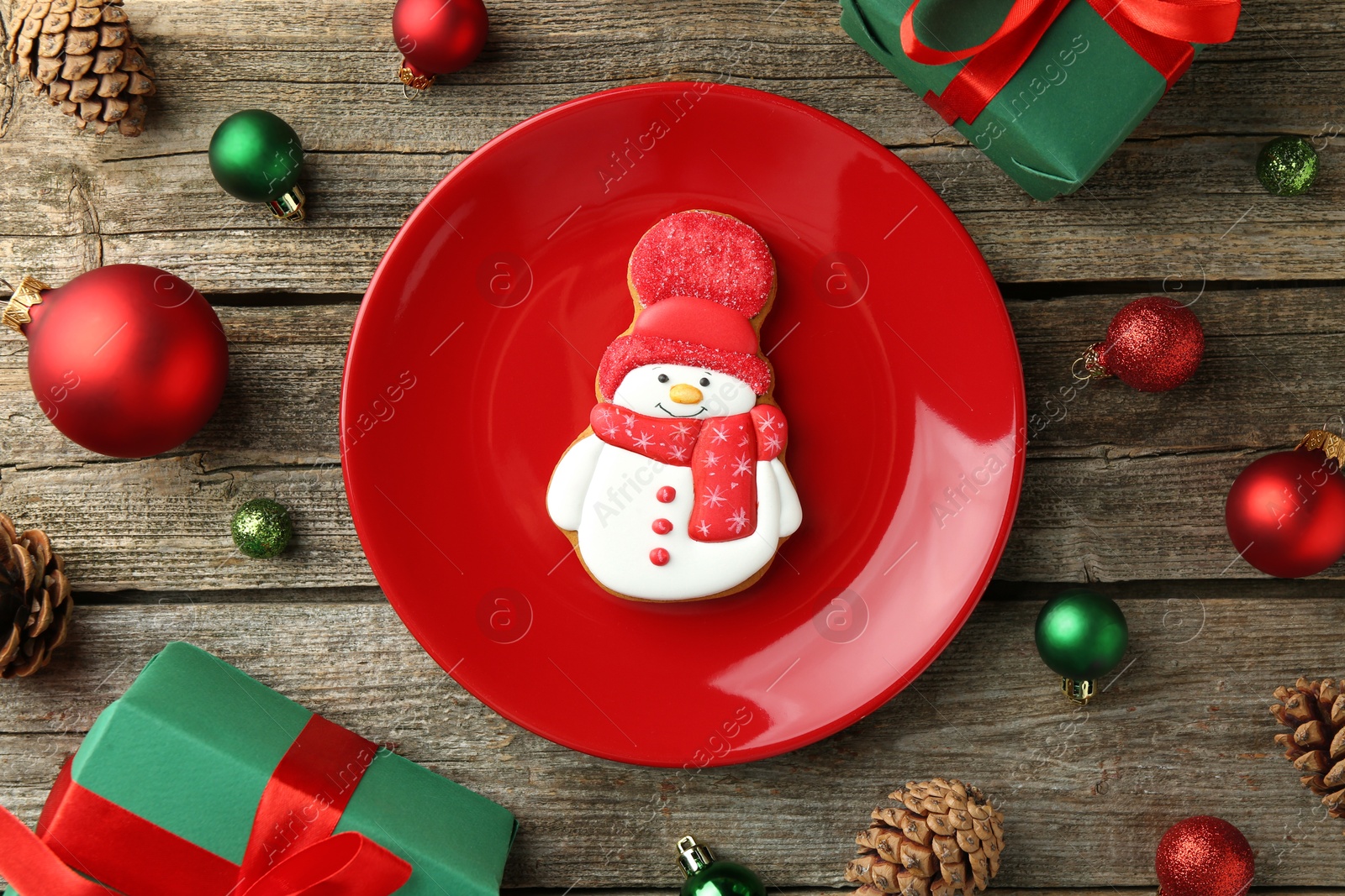 Photo of Delicious cookie in shape of snowman and Christmas decor on wooden table, flat lay