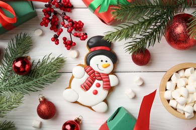 Photo of Delicious cookie in shape of snowman, marshmallows and Christmas decor on white wooden table, flat lay