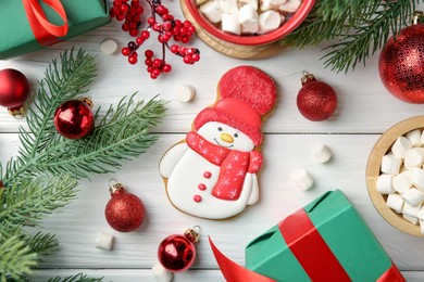 Photo of Delicious cookie in shape of snowman, marshmallows and Christmas decor on white wooden table, flat lay