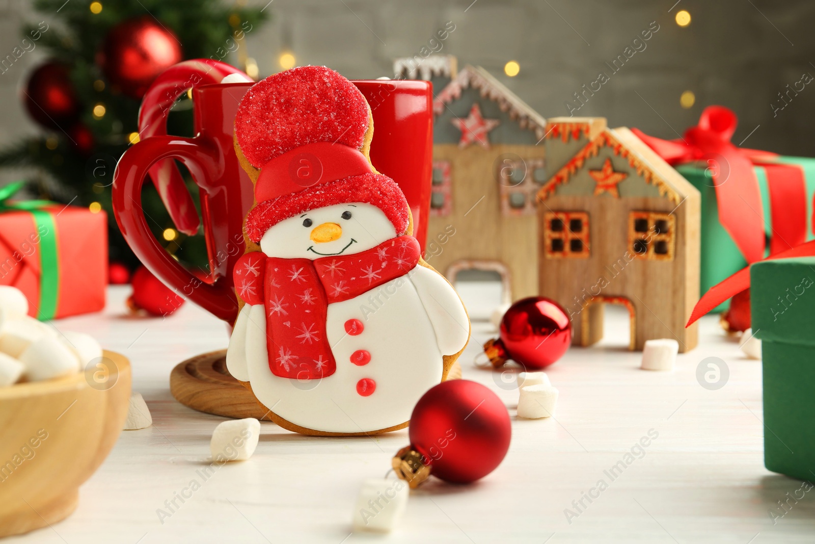 Photo of Delicious cookie in shape of snowman, cup with cocoa and Christmas decor on white wooden table