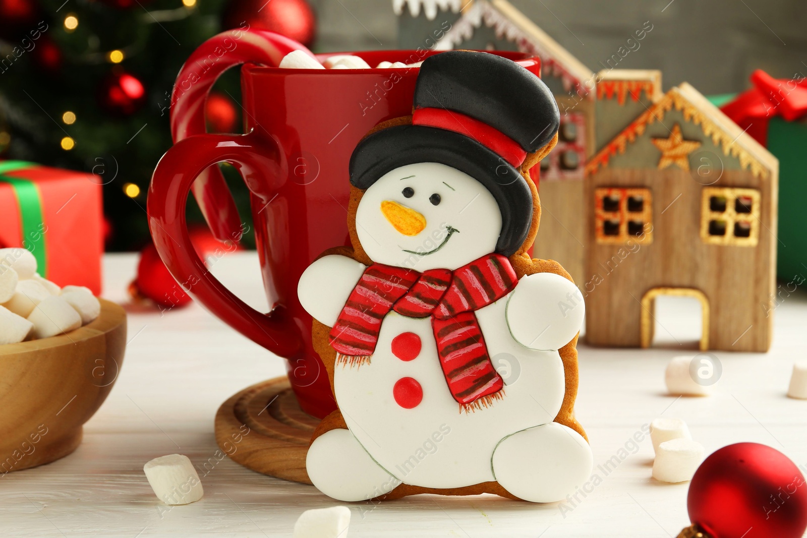 Photo of Delicious cookie in shape of snowman, cup with cocoa and Christmas decor on white wooden table, closeup