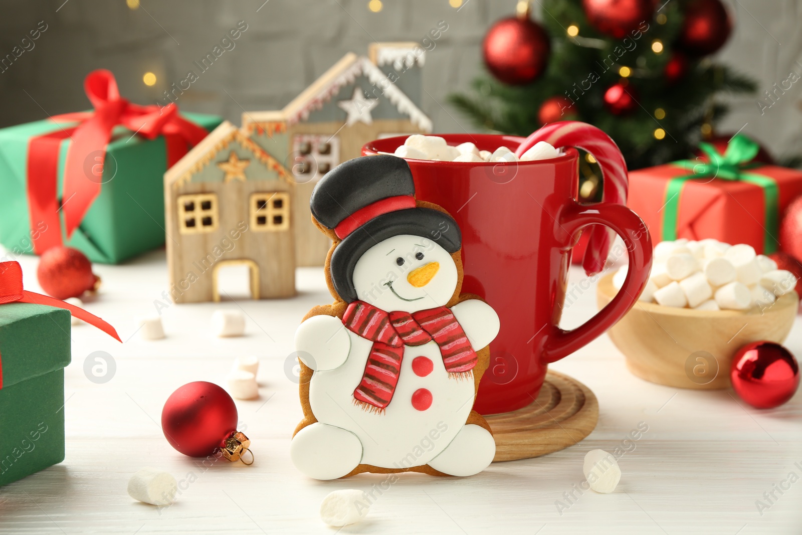 Photo of Delicious cookie in shape of snowman, cup with cocoa and Christmas decor on white wooden table