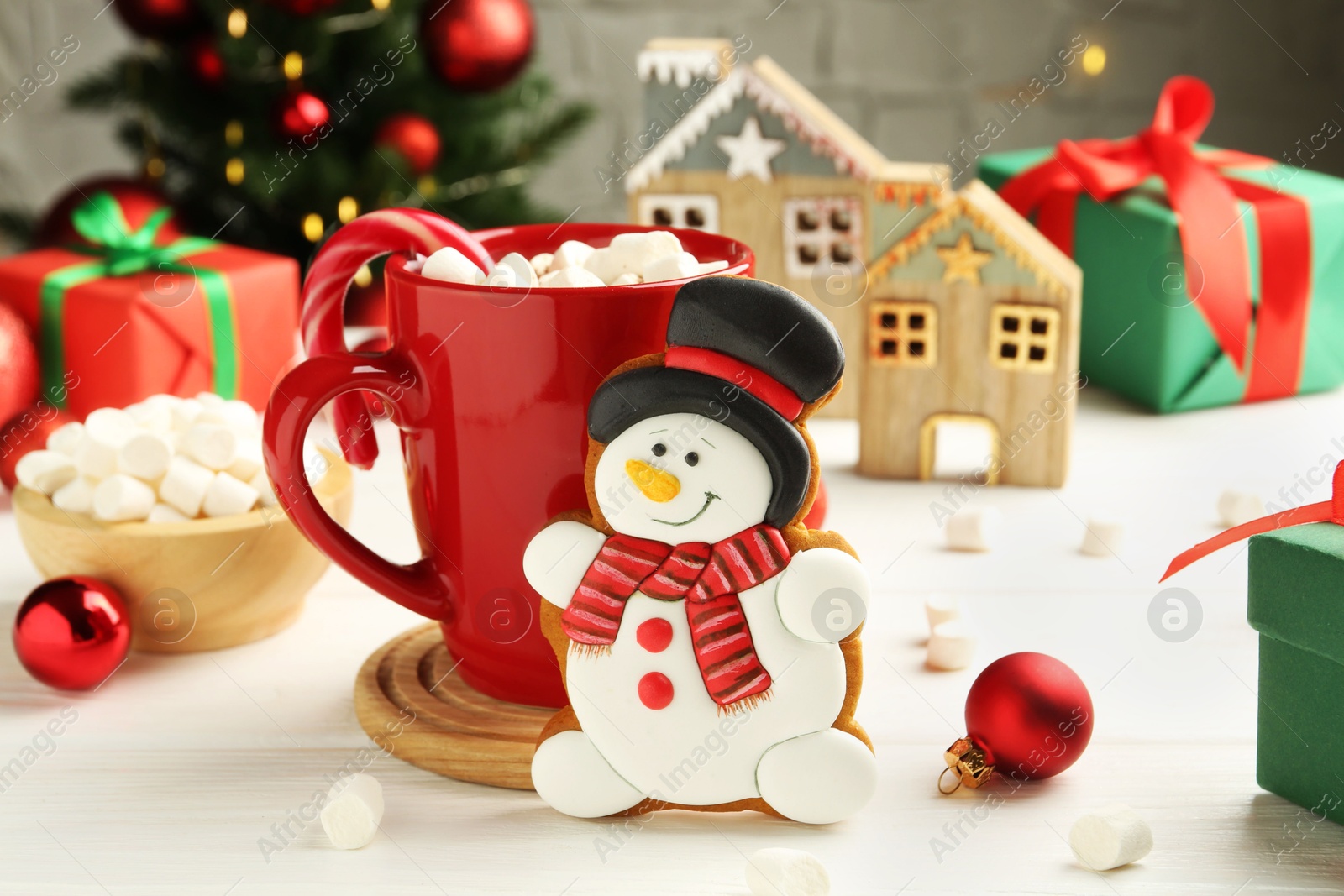 Photo of Delicious cookie in shape of snowman, cup with cocoa and Christmas decor on white wooden table