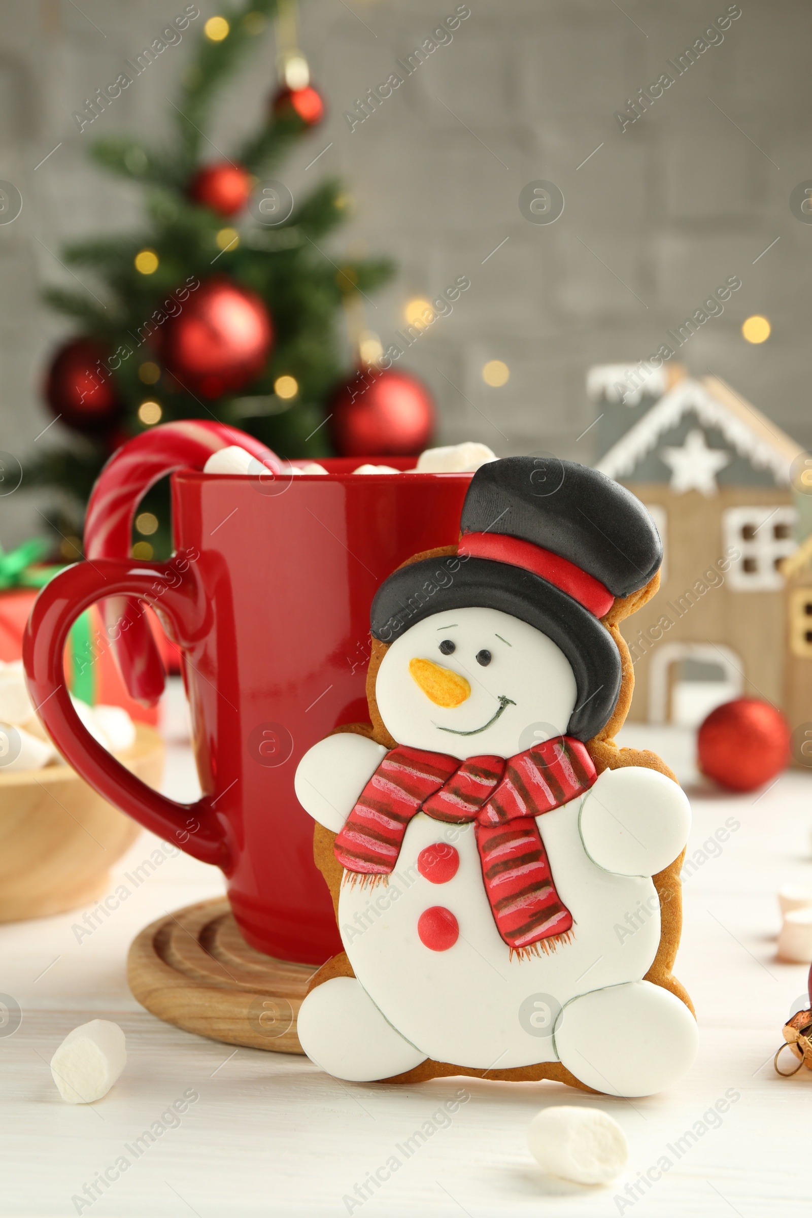 Photo of Delicious cookie in shape of snowman, cup with cocoa and Christmas decor on white wooden table