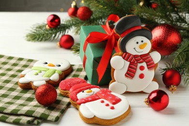 Photo of Delicious cookies in shape of snowmen and Christmas decor on white wooden table, closeup