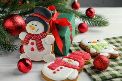 Photo of Delicious cookies in shape of snowmen and Christmas decor on white wooden table, closeup