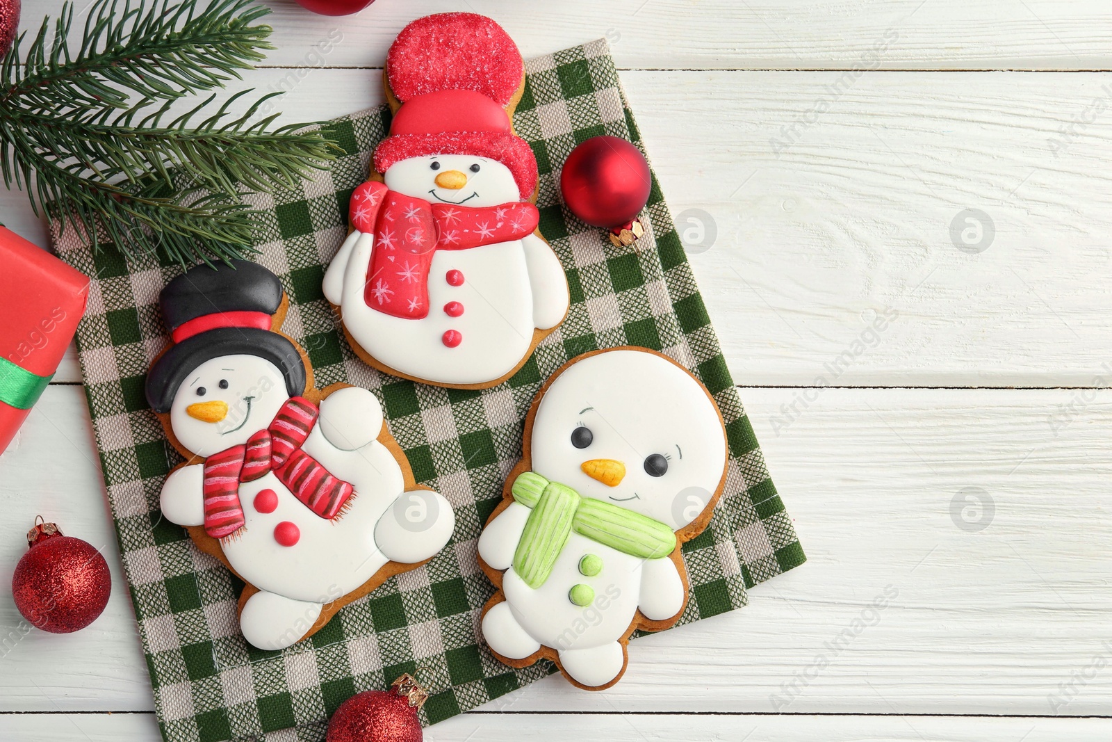 Photo of Delicious cookies in shape of snowmen and Christmas decor on white wooden table, flat lay. Space for text