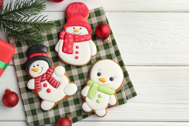 Photo of Delicious cookies in shape of snowmen and Christmas decor on white wooden table, flat lay. Space for text