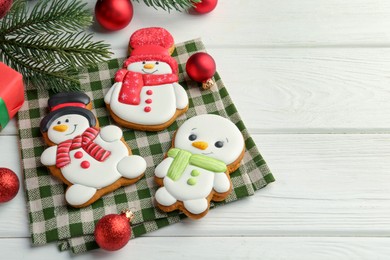 Photo of Delicious cookies in shape of snowmen and Christmas decor on white wooden table, above view. Space for text