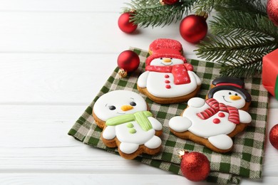 Photo of Delicious cookies in shape of snowmen and Christmas decor on white wooden table, closeup. Space for text