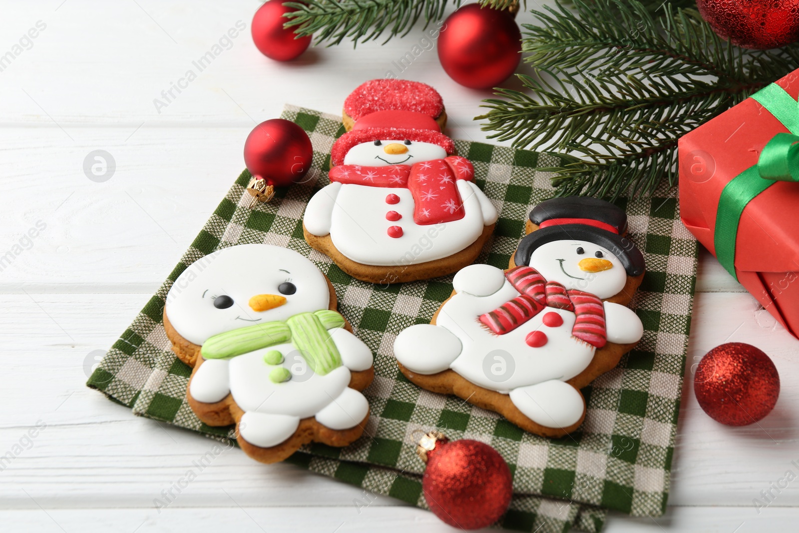 Photo of Delicious cookies in shape of snowmen and Christmas decor on white wooden table, closeup