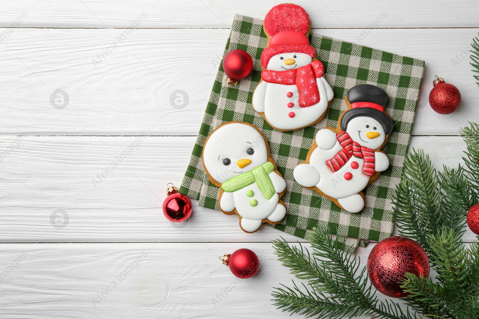 Photo of Delicious cookies in shape of snowmen and Christmas decor on white wooden table, flat lay. Space for text