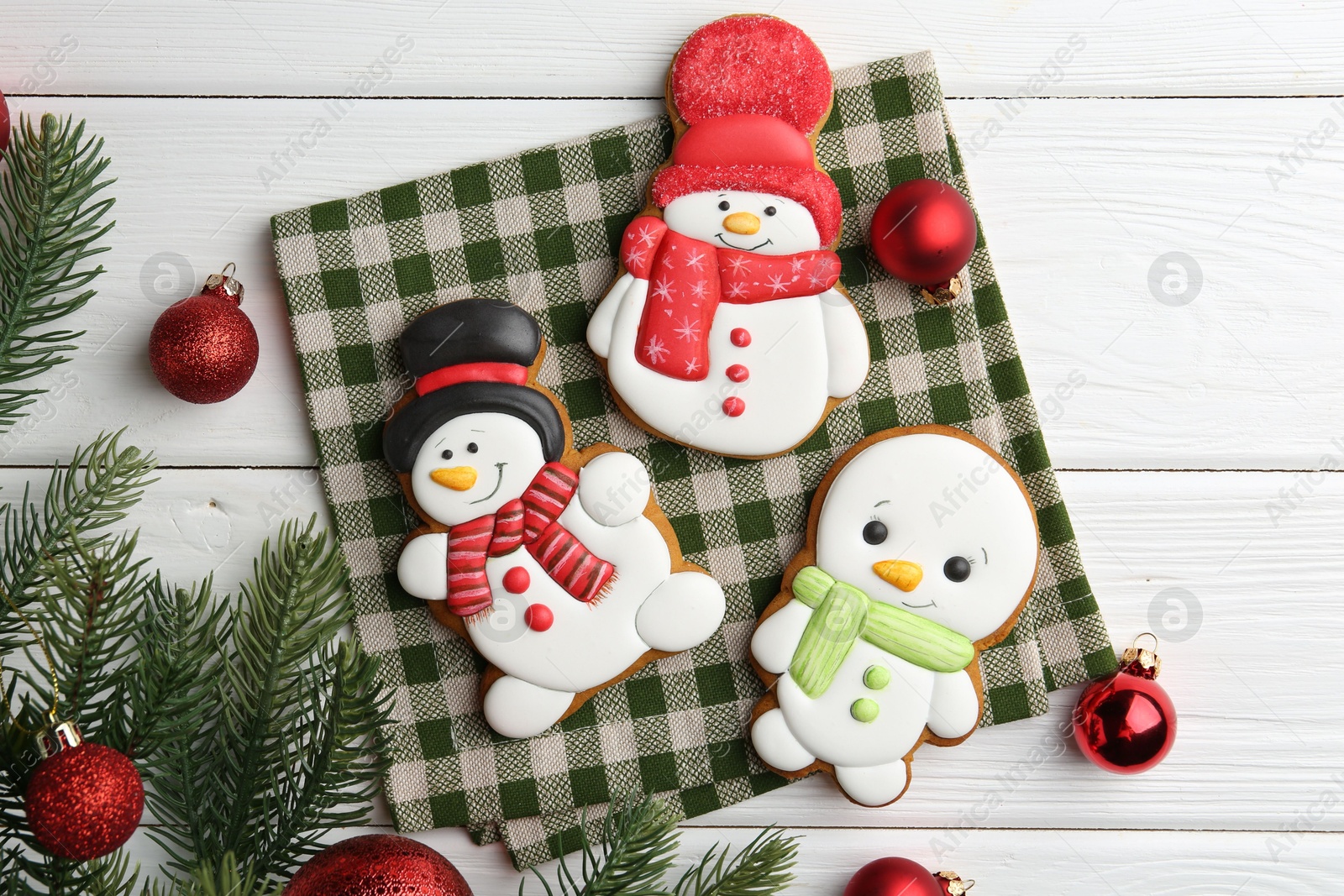 Photo of Delicious cookies in shape of snowmen and Christmas decor on white wooden table, flat lay