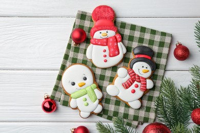 Photo of Delicious cookies in shape of snowmen and Christmas decor on white wooden table, flat lay. Space for text