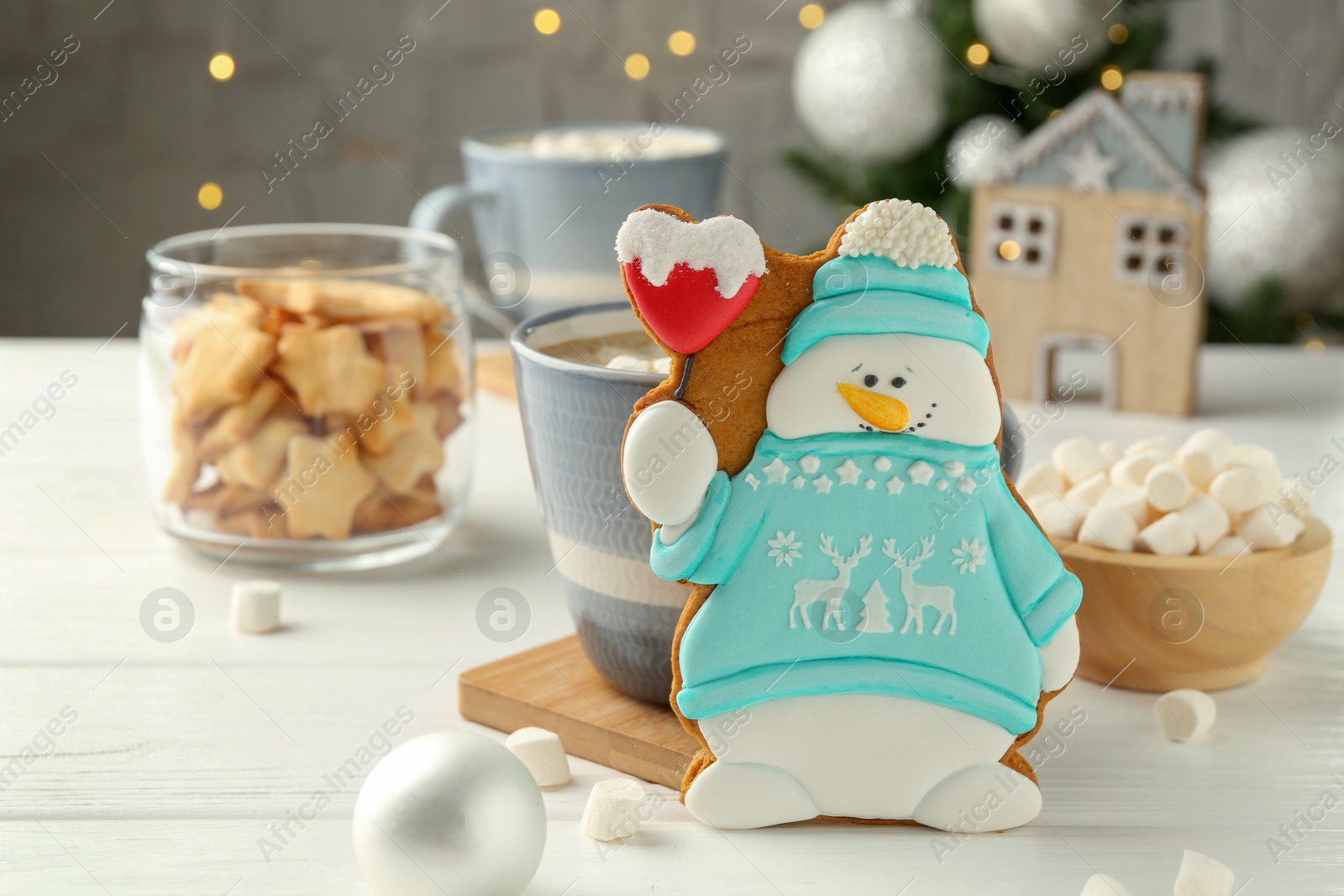 Photo of Delicious cookie in shape of snowman, cup with cocoa and Christmas decor on white wooden table