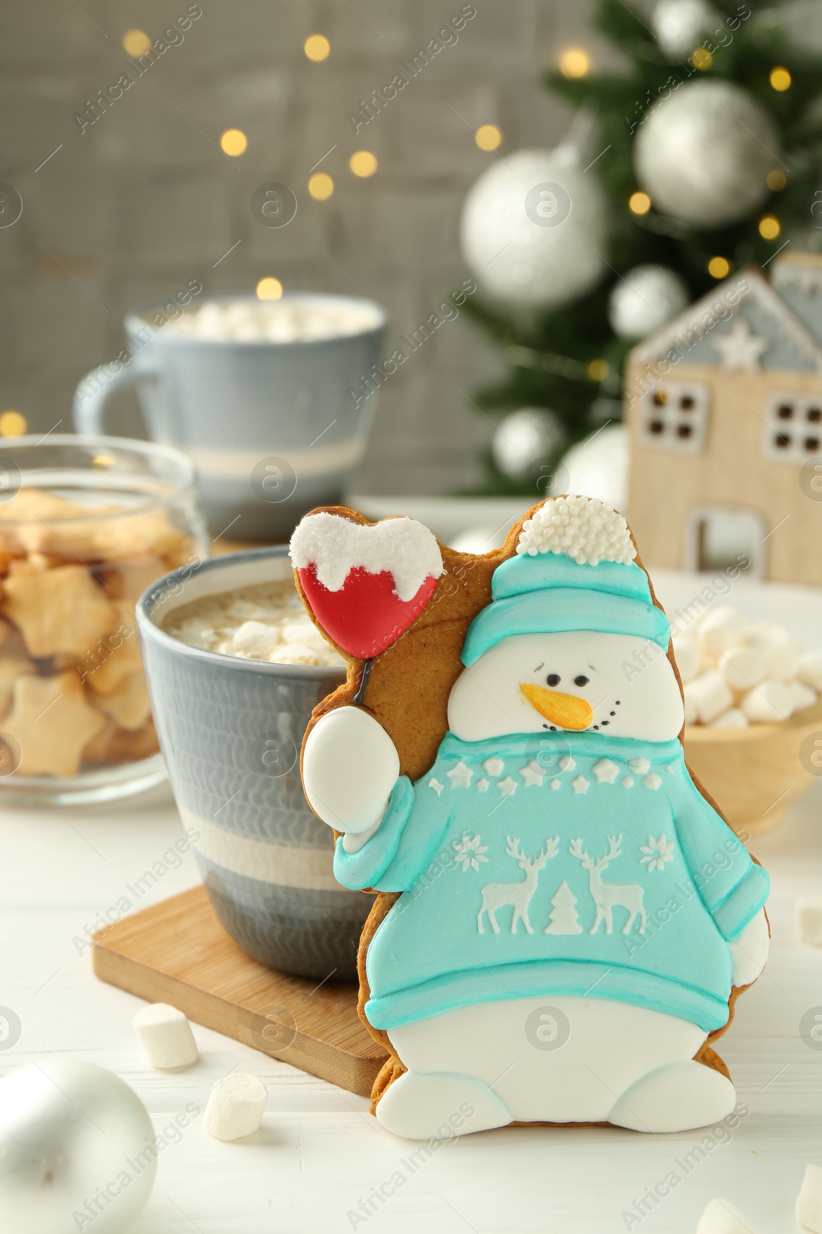 Photo of Delicious cookie in shape of snowman, cup with cocoa and Christmas decor on white wooden table