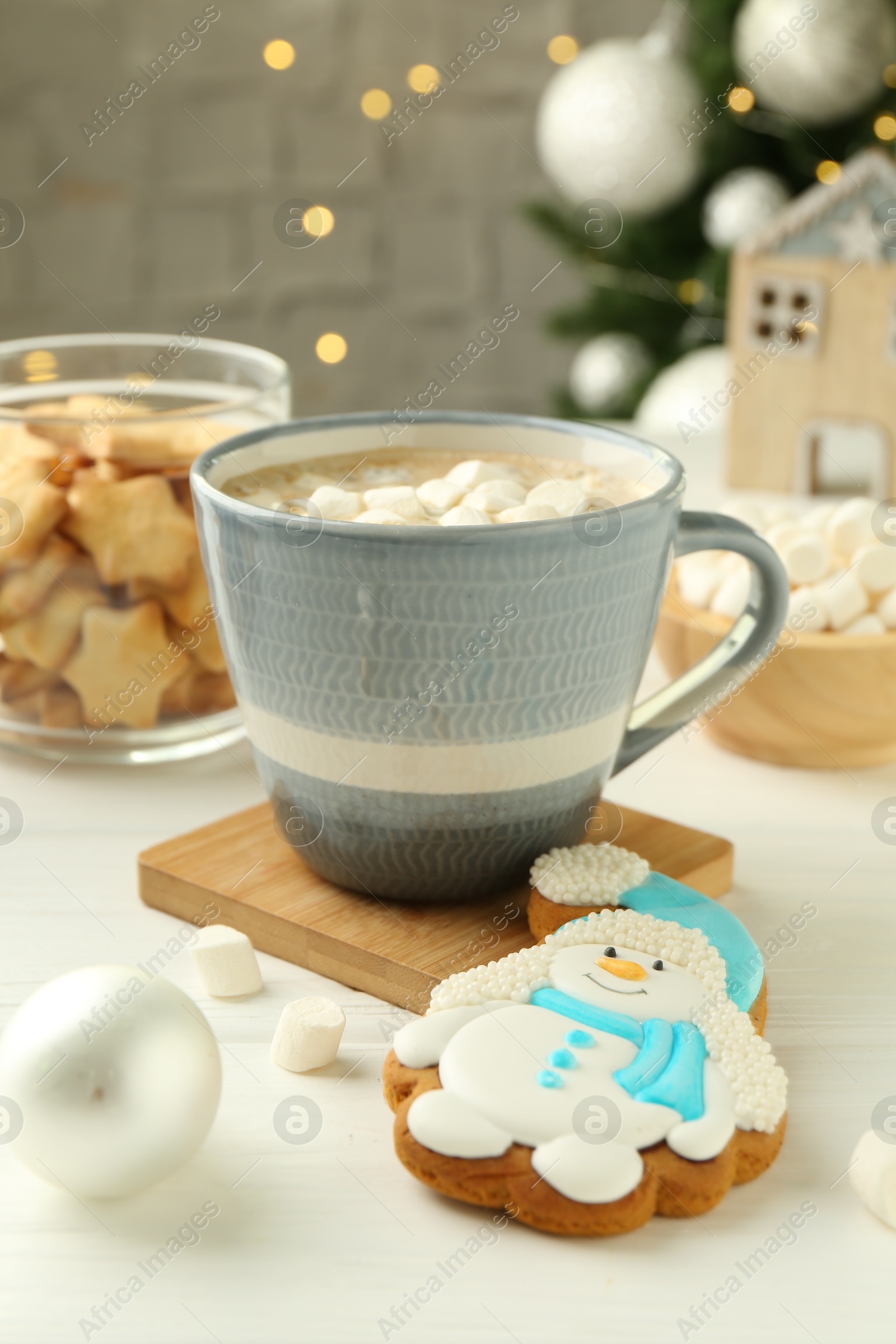 Photo of Delicious cookie in shape of snowman, cup with cocoa and Christmas decor on white wooden table