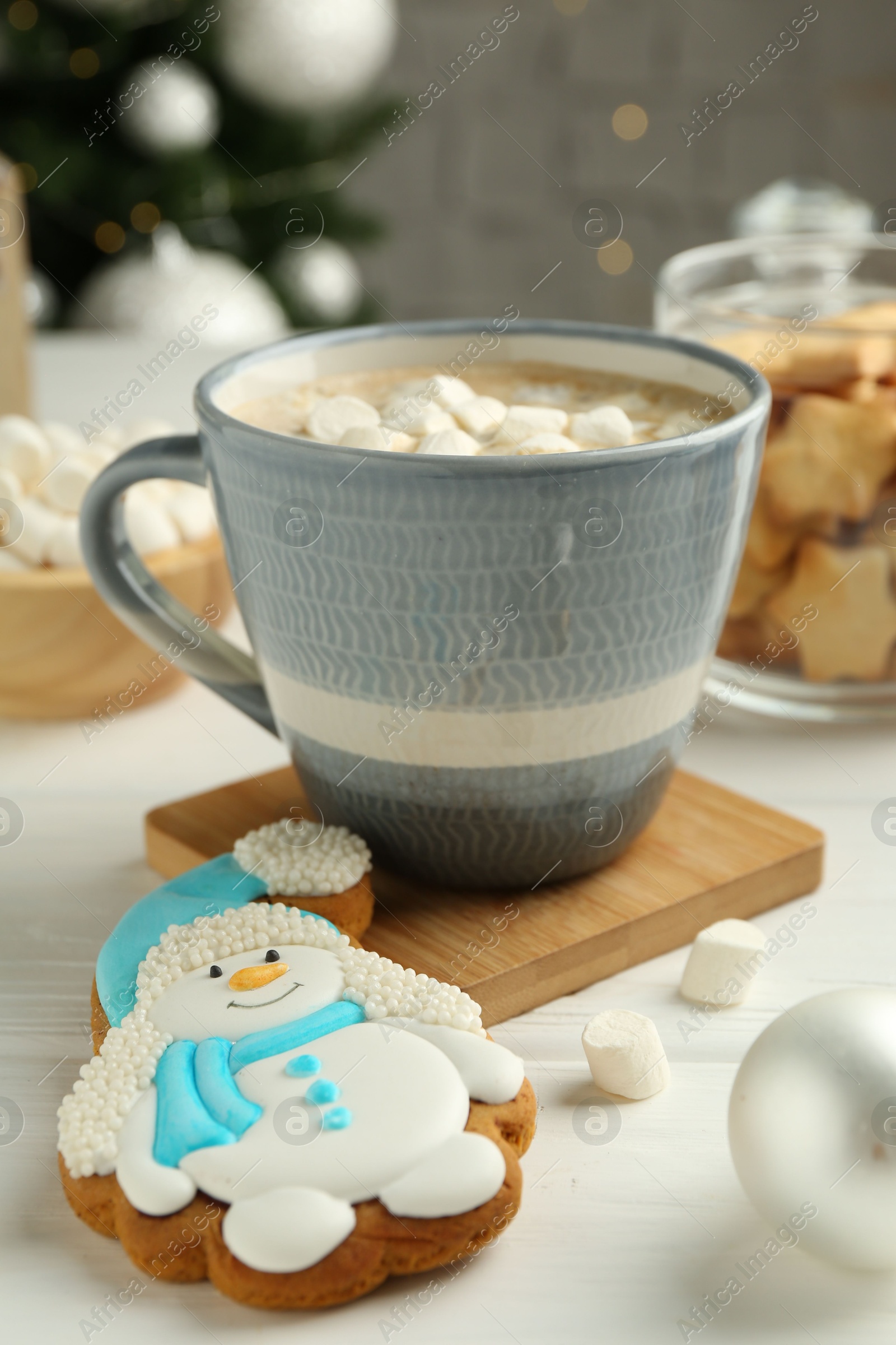 Photo of Delicious cookie in shape of snowman, cup with cocoa and Christmas decor on white wooden table, closeup