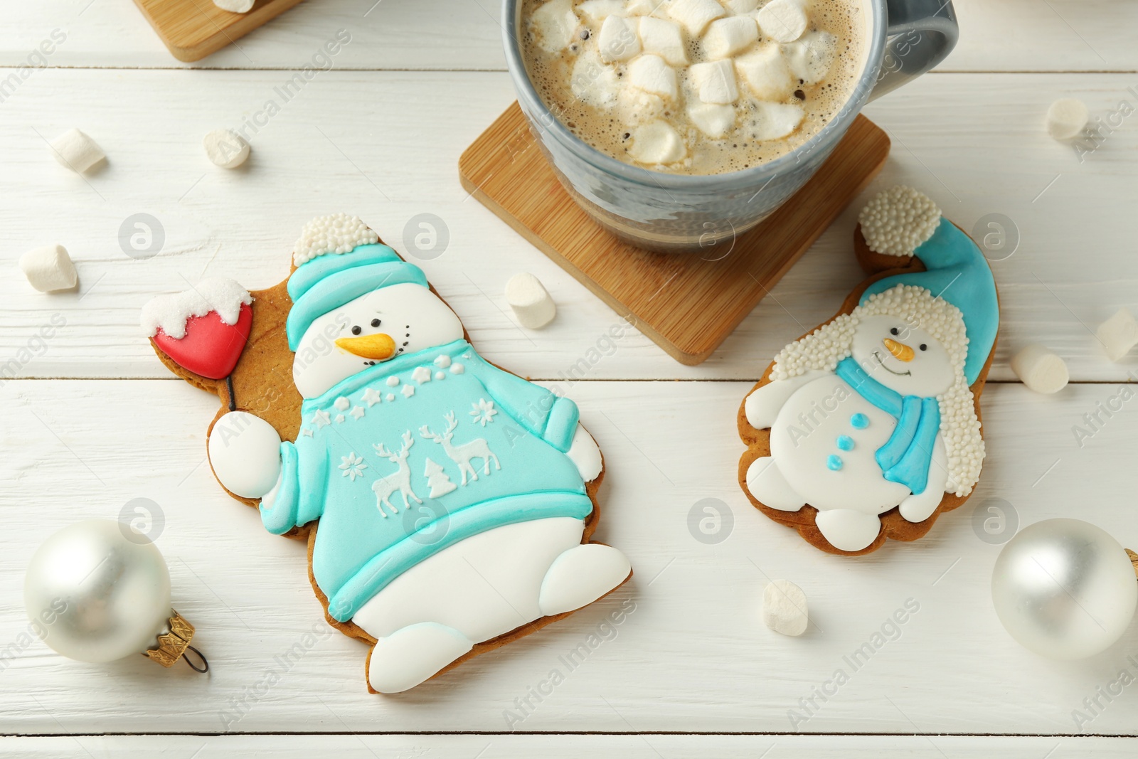 Photo of Delicious cookies in shape of snowmen, cup with cocoa and Christmas decor on white wooden table, flat lay