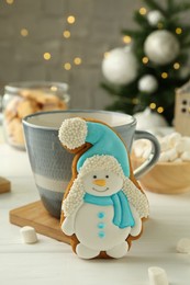 Photo of Delicious cookie in shape of snowman, cup with cocoa and Christmas decor on white wooden table