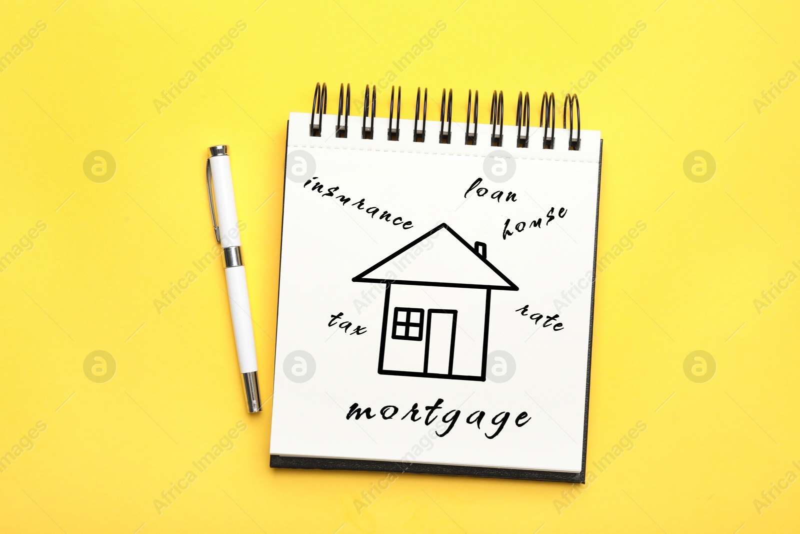 Image of Notebook with drawing of house and words on yellow background, top view. Mortgage